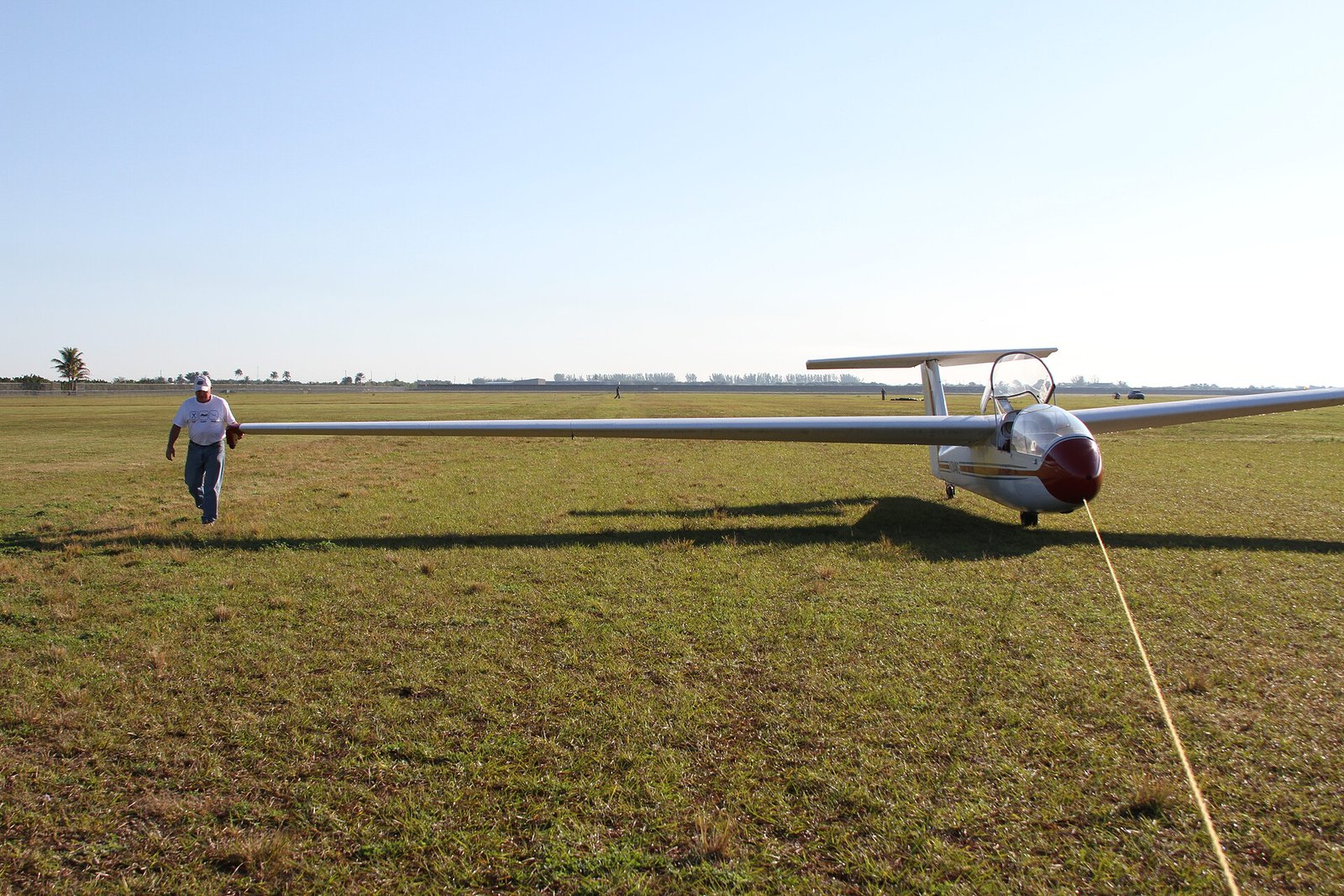 Pilot walking a Super Blanik L-23 out to the runway by the wing