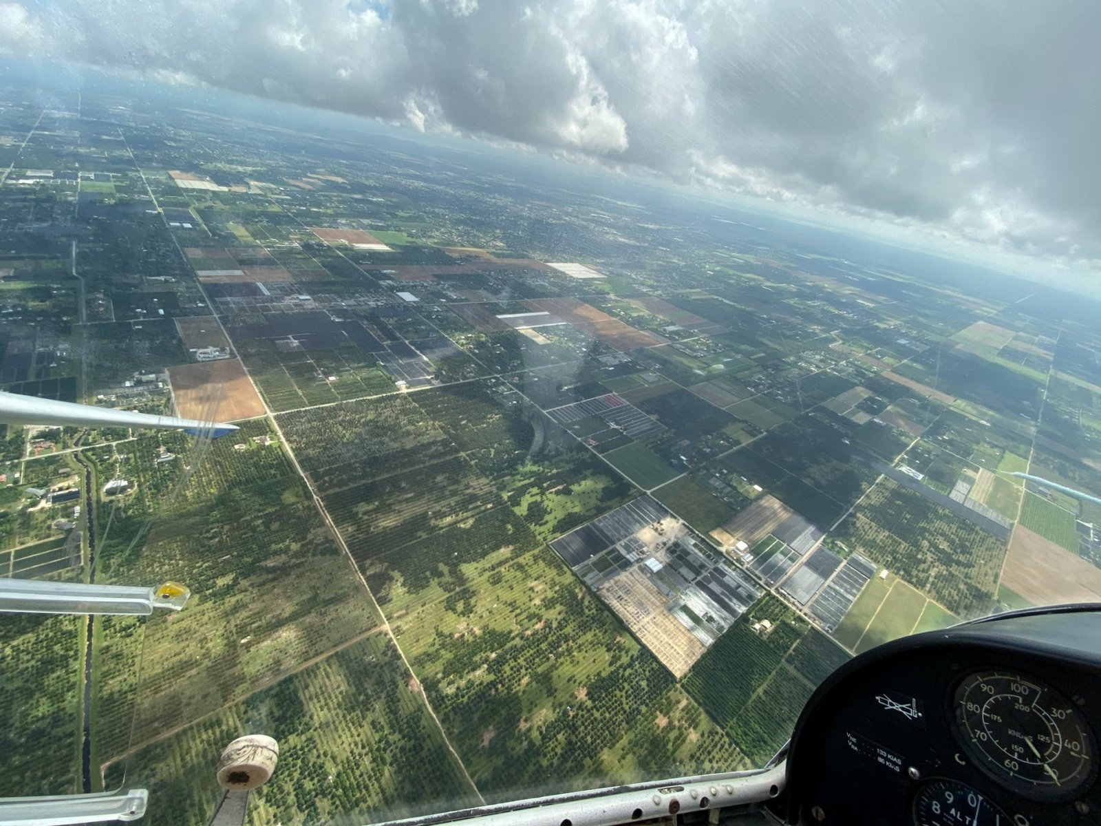 Cockpit view over the patchwork fields of South Florida with cumulus building